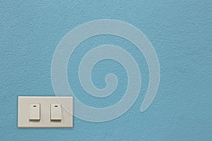 White electric switch on blue cement wall.