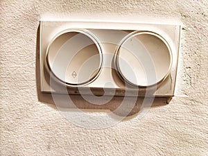 A white electrical outlet and light switch mounted on a textured wall