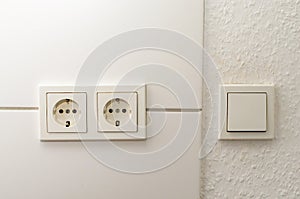 White electrical outlets and light switch on white wall