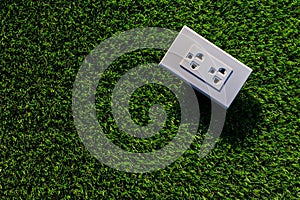 The white electrical plug socket on the green grass.