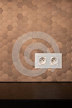White electrical sockets in copper tile wall