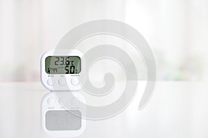 White electronic hygrometer on white table in front of the window photo