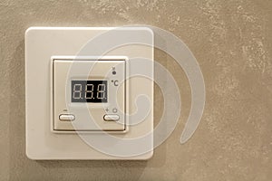 White electronic programmable digital thermostat on light wall copy space background. Climate control, comfortable home