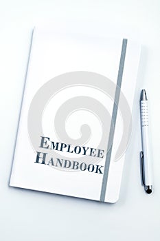 White Employee Handbook or manual with White pen on a white table in an office.