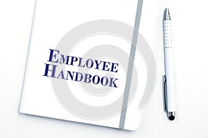 White Employee Handbook or manual with White pen on a white table in an office.