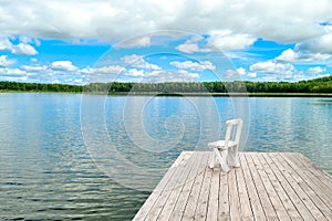 White empty deck chair at the lake dock.