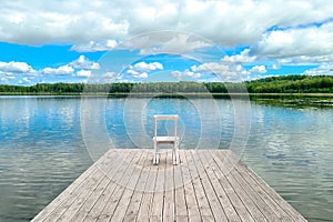 White empty deck chair at the lake dock.