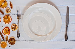 White empty dining plate with cutlery on a white wooden surface