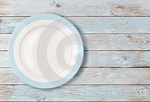 White empty dinner plate with blue border on wooden table