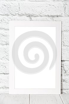 White empty photo frame against brick wall. Mockup with copy space