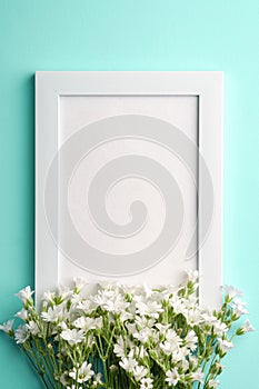 White empty photo frame mockup with mouse-ear chickweed flowers on blue background