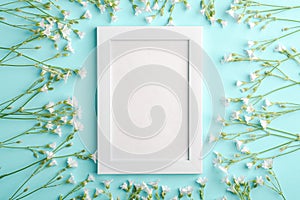 White empty photo frame mockup with mouse-ear chickweed flowers on blue background