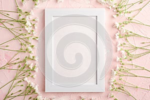 White empty photo frame mockup with mouse-ear chickweed flowers on pink textured background