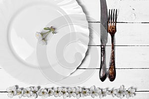White empty plate with cutlery on a wooden surface
