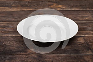 White empty plate on dark wooden table