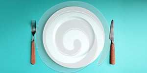 White Empty Plate with Fork and Knife Lay on Blue Table Background. Food Shortage, World Food Crisis Issue