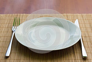 White empty plate, fork and knife on the table