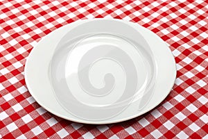 White empty plate on red gingham tablecloth