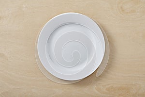 White empty plate on wooden table. Top view.