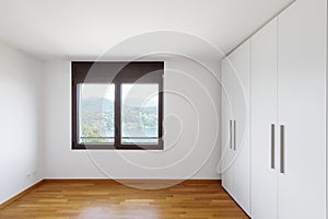 White empty room with windows overlooking the lake and large white wardrobe