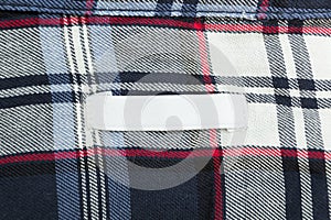 White empty tag on fabric with a square pattern. Empty space for text