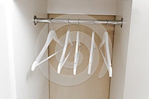 White empty wardrobe closet with hangers. Wooden white hangers on a rod. Store, sale, advertisement concept