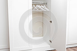 White empty wardrobe closet with hangers. Wooden white hangers on a rod. Store, sale, advertisement concept