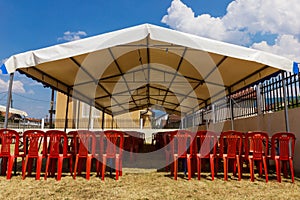 White entertainment tent with red plastic chairs