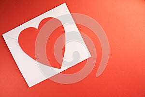 A white envelope with a bright red paper heart ontop of it again