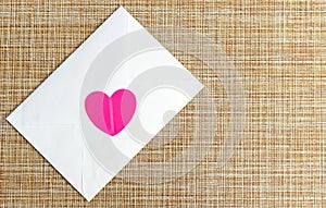 A white envelope with a pink heart. Love letter. Invitation to the wedding.