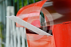 White envelope in red mail box on home fence