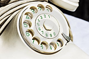 White European rotary dial telephone with green numbers on the finger wheel. Old vintage rotary dial telephone, close-up fragment