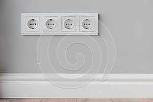 White European sockets on gray concrete wall in loft style, with high polyurethane baseboard