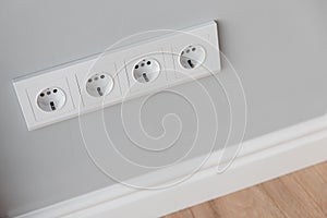 White European sockets on gray concrete wall in loft style, with high polyurethane baseboard