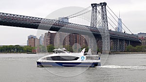 White excursion motor boat underway on the East River on background, of Williamsburg Bridge, New York, NY, USA