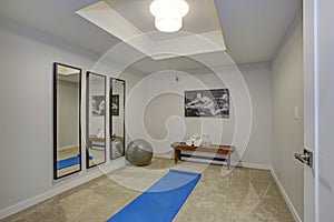 White exercise room with a bench, mirror and workout accessories
