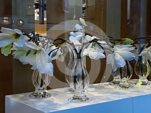 White exotic artificial flowers  in  vase on window top in street store window vitrine photo