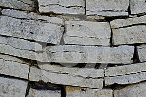 White exterior stone wall with sagging rectangular bricks