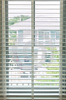 White fabric roller blinds on the plastic window with wood texture. Window with open modern horizontal white blinds indoor. White