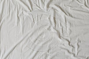 White fabric texture background. Wrinkled, crumpled fabric. Top view of unmade bed sheet after night sleep. Soft focus