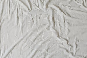 White fabric texture background. Wrinkled, crumpled fabric. Top view of unmade bed sheet after night sleep. Soft focus photo