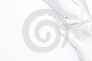 White fabric on white background with copy space. Glossy white satin texture. Crumple white cloth on white background