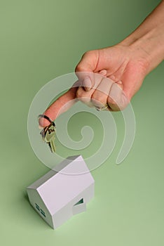 White family paper house. House keys in hand on mint background paper. Minimalistic and simple concept, style. Copy space.