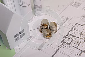 White family paper house , stack of money coins, house projects plan and blueprints on mint background paper. Minimalistic and