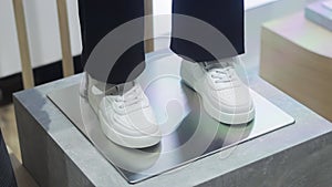 White fashionable sneakers with black pants on a mannequin in a clothing store, close-up. Slow motion, close-up. Slow