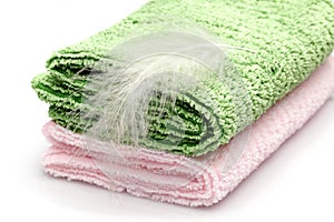 White feather on pink and green coloured towel