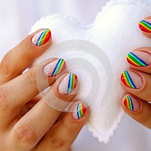 White felted heart in femaile hands with rainbow manicure. Love, valentine, lgbt, pride concept