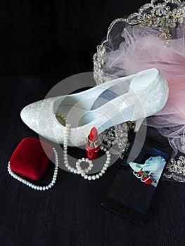 White female shoe with high heels, red lipstick and smartphone with the photo in the screen
