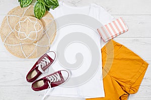 White female t shirt mock up flat lay on wooden background. Top view and copy space. Mockup t-shirt and summertime. Template blank