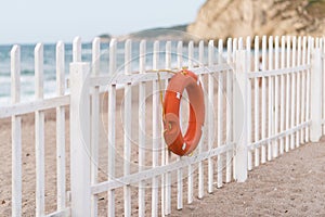 White fence on beach with a life buoy